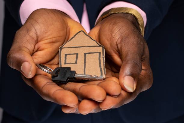 paper house and key in the palm of a black person's hand